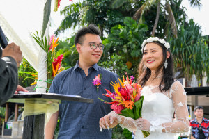 Asian couple exchanging vows at the altar in Warwick beach wedding