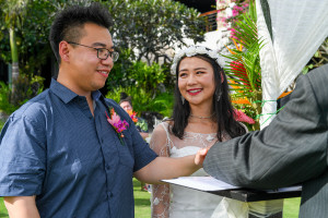 Closeup of Asian groom places hand on the bible while exchanging vows in Fiji Warwick