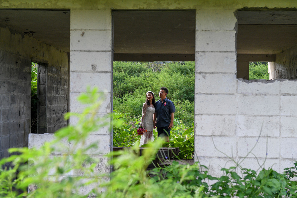 Married Asian couple standing behind abandoned building in Warwick Fiji photoshoot