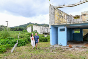 Wide shot of newly married couple standing against abandoned building in Warwick Fiji