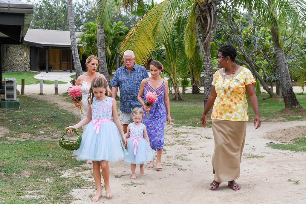 Flower girls walking down sandy beach in Plantation Island Resort