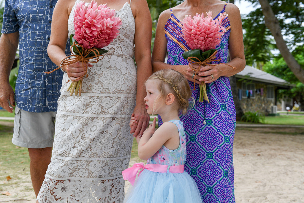 Flower girl holds mom hold bouquet of tropical flowers during Plantation Island Fiji Resort Wedding