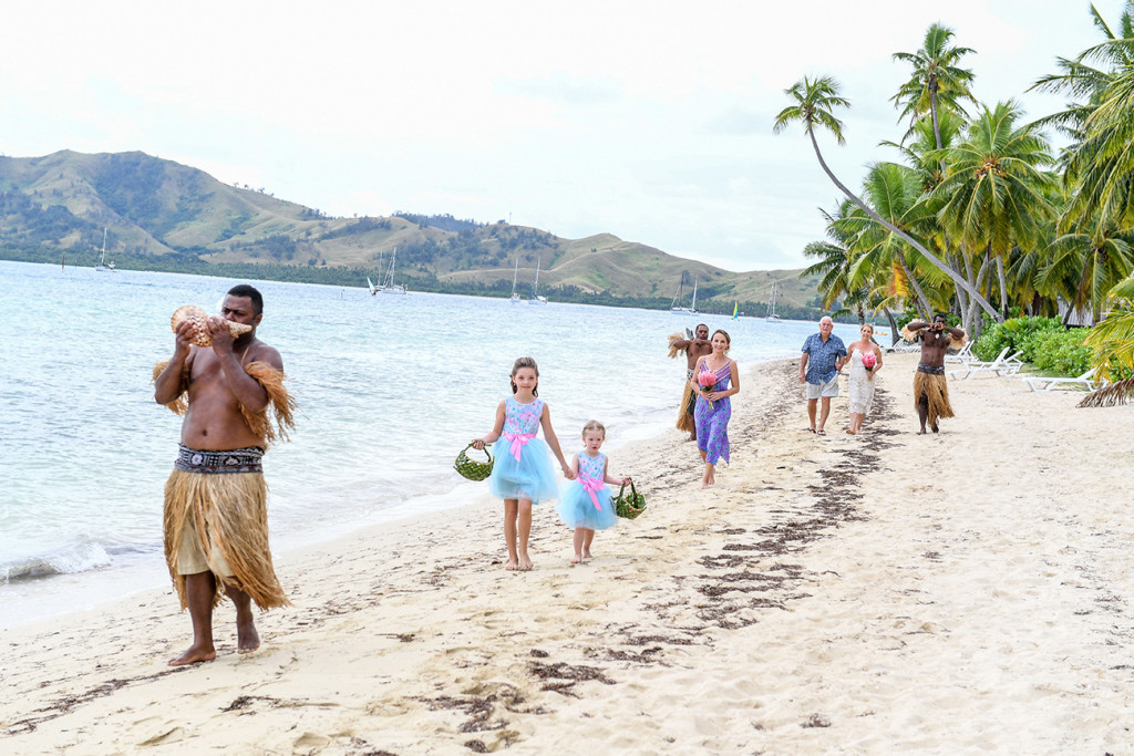 Flower girls and bride walk along the sea on beach at Plantation Island Resort Fiji wedding