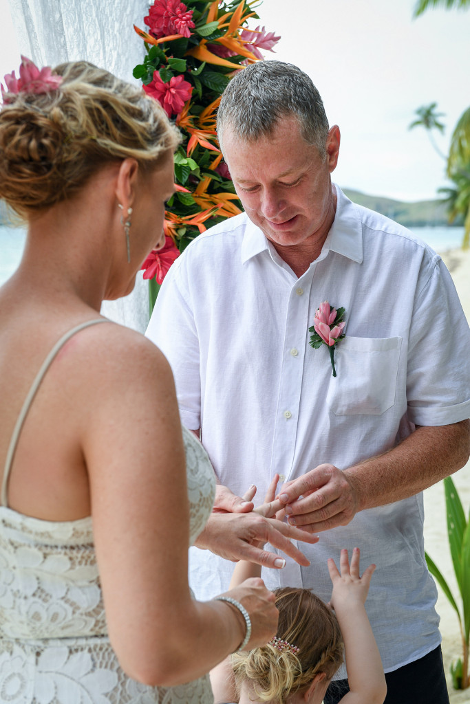 Groom puts ring on his bride in beach wedding Plantation Island Resort Fiji