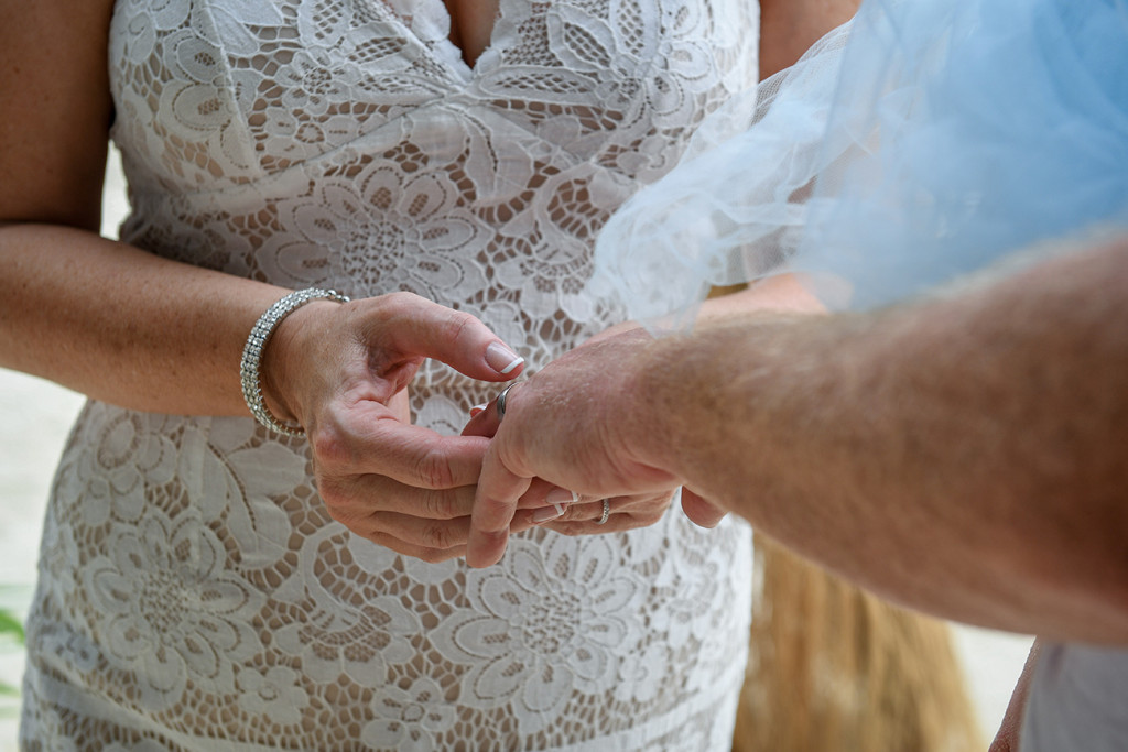 Closeup of bride putting ring on groom in Fiji wedding