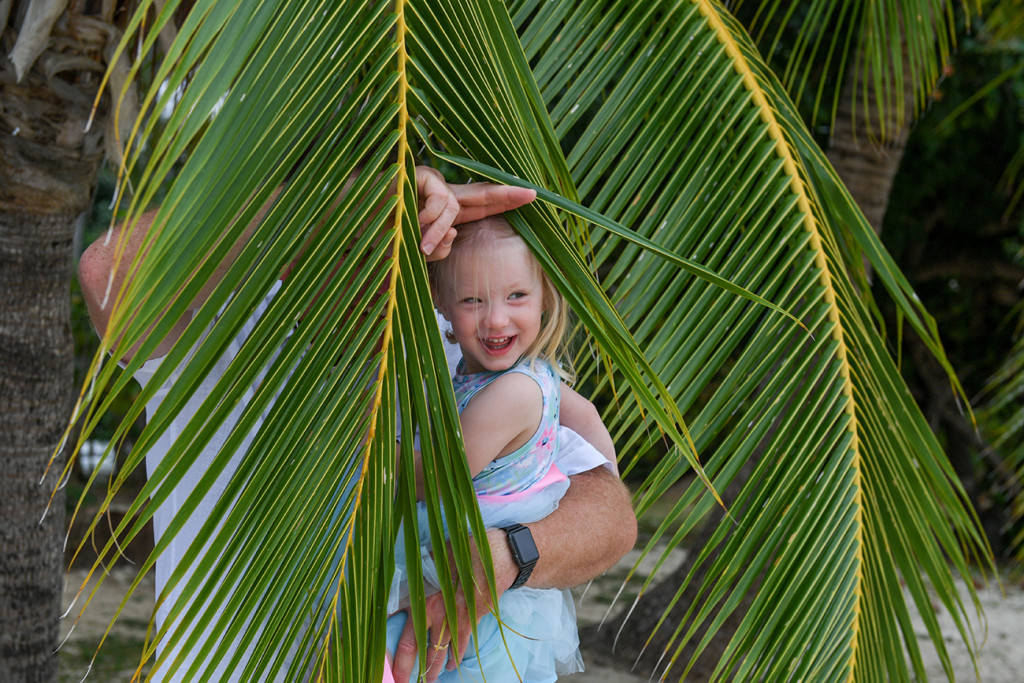 Happy flower girl hiding in the palm trees in Fiji Island Resort