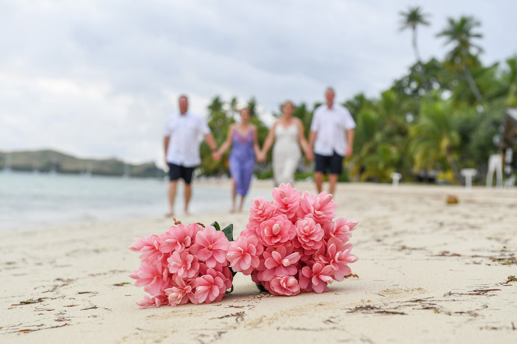 Bouquet of tropical flowers in the foreground and family in background at Fiji tropical wedding background blurred