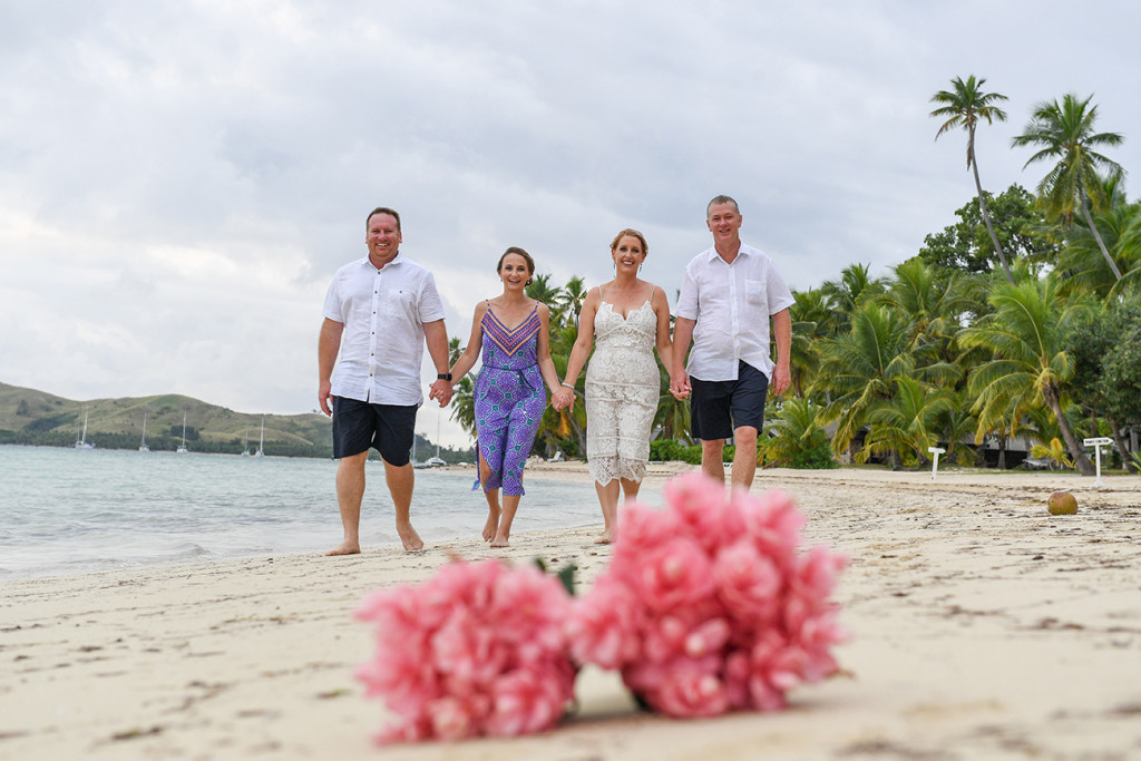 Blurred Bouquet of tropical flowers in the foreground and family in background at Fiji tropical wedding