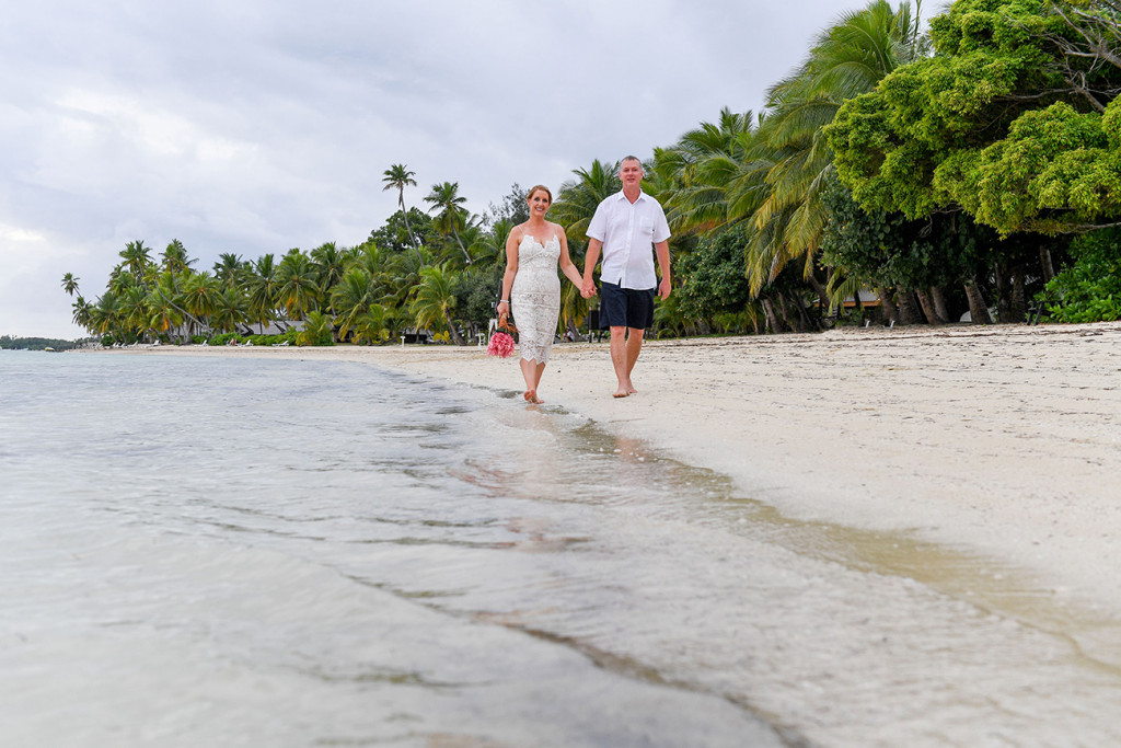 Bride and groom stroll by the sea in Plantation Island Resort Fiji