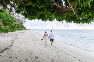 Back shot of bride and groom strolling on Fiji island beach
