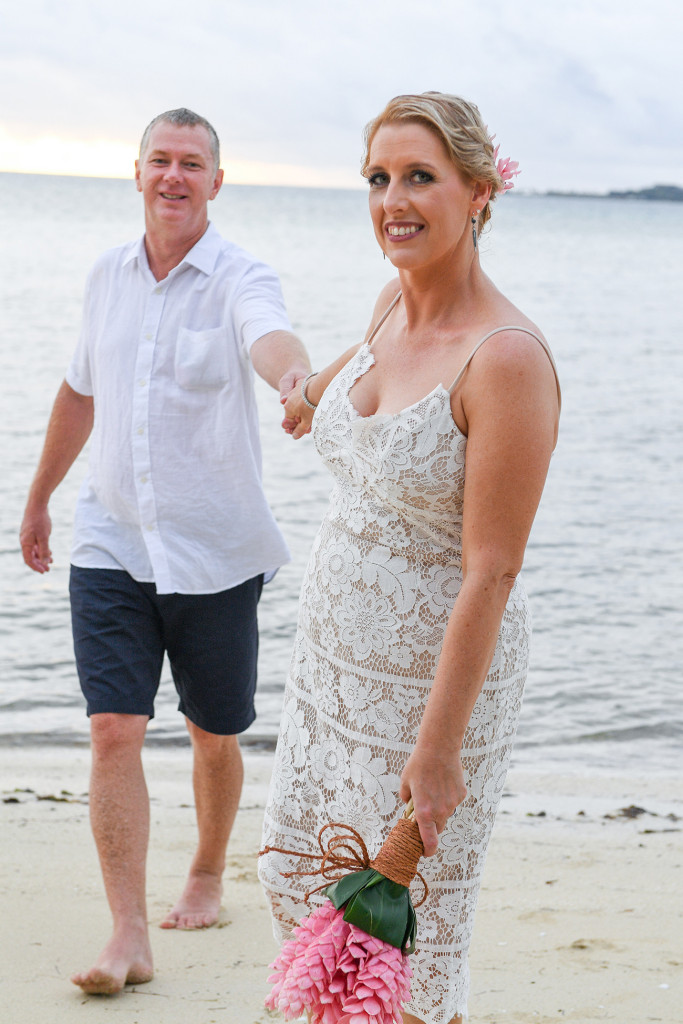 Bride holds onto groom against the Fiji sea