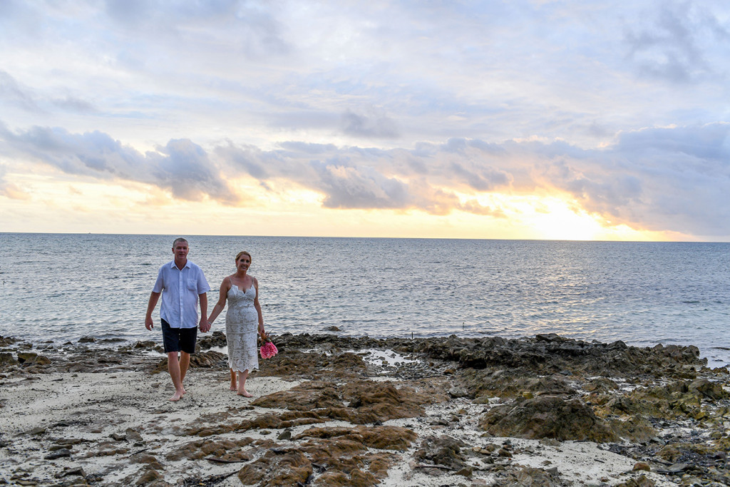 Newly married couple walk on coral rocks in Fiji Plantation Island Resort