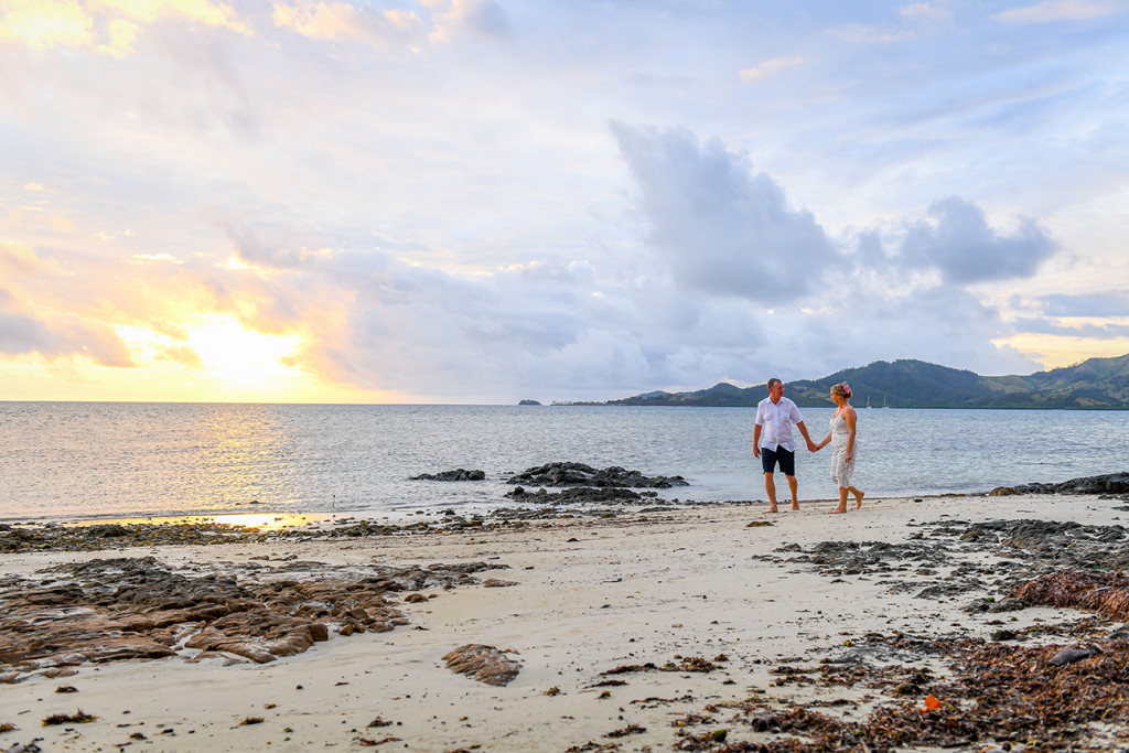Bride and groom stroll on the beach in fiery Fiji wedding