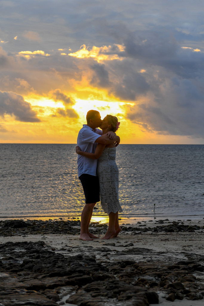 Newly married Kiss against the golden fiery sunset against the ocean in Fiji Island