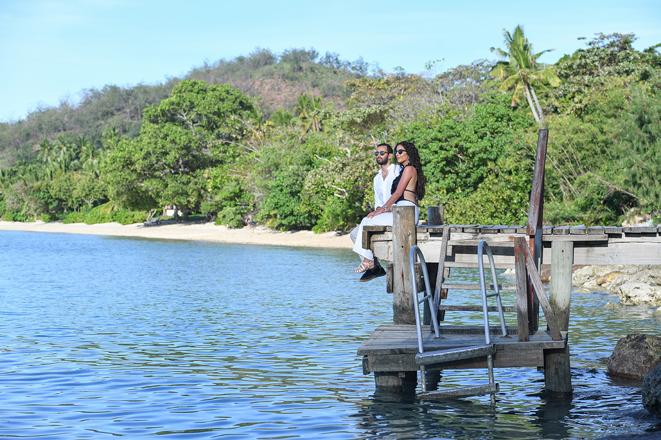 Newly married couple sit on the edge of the deck at Likuliku Resort Fiji