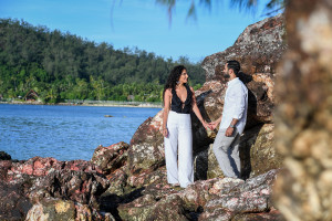 Newly wed couple stand on a huge rock with ocean in background in Likuliku Honeymoon Resort Fiji