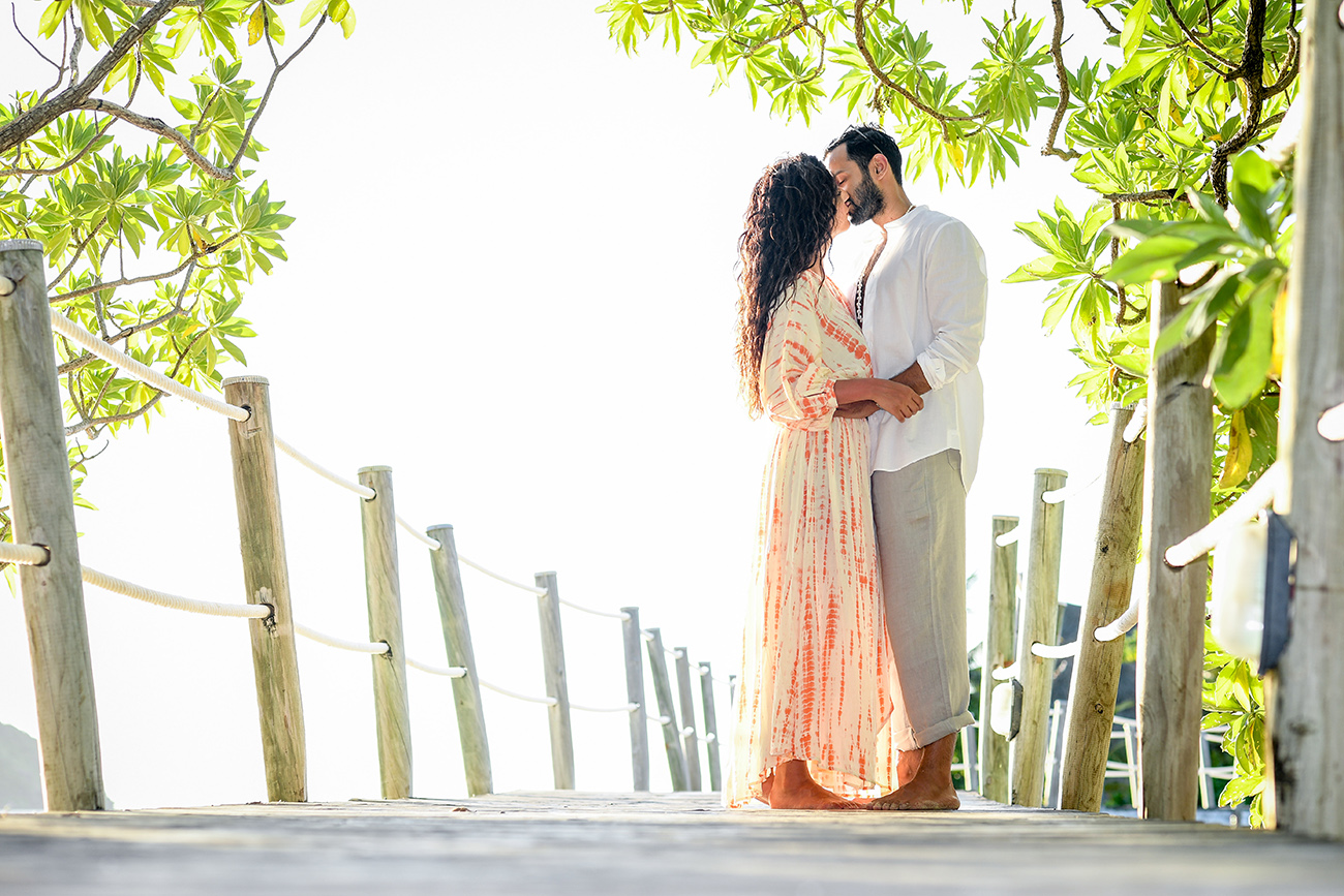 Honeymooning couple kiss on wooden bridge at Likuliku Honeymoon Resort Fiji