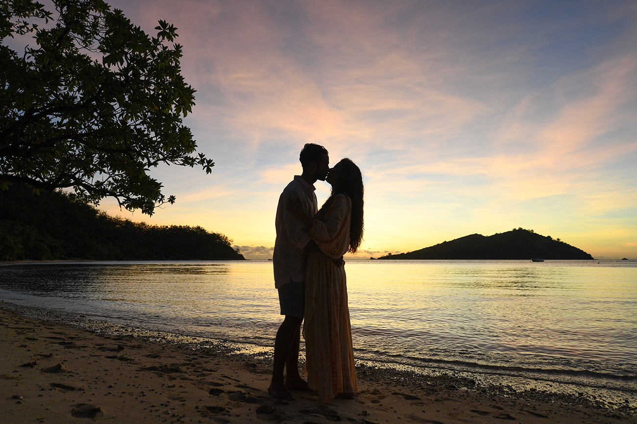 Silhouette of honeymoon couple kissing against the sunset in Likuliku Fiji