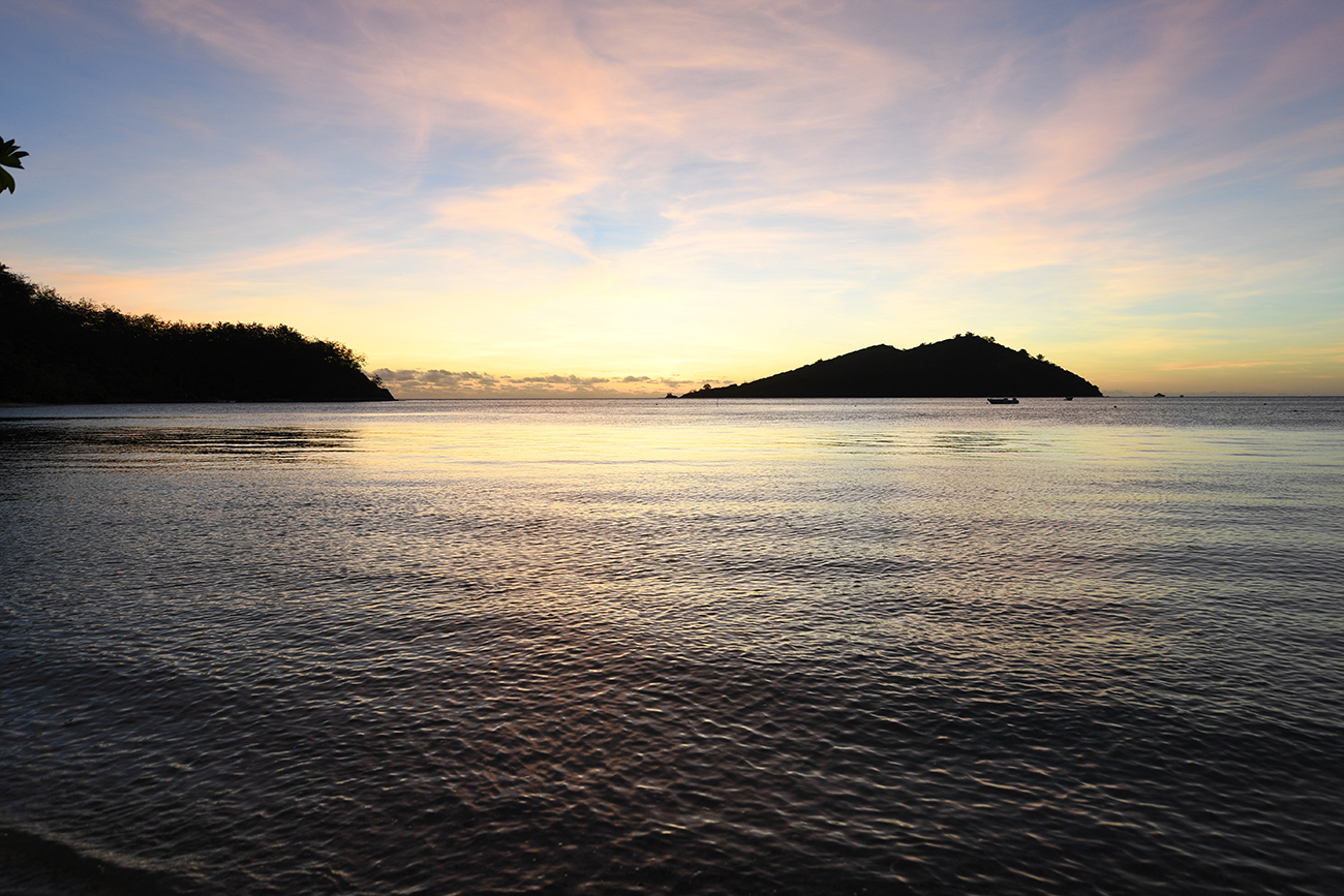 Stunning silhouette island against pink and gold sunset captured by Anais Chaine