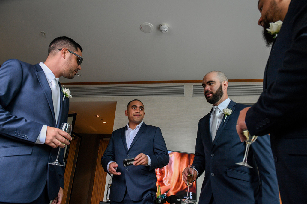Groomsmen drink champagne as they wait for the cermony