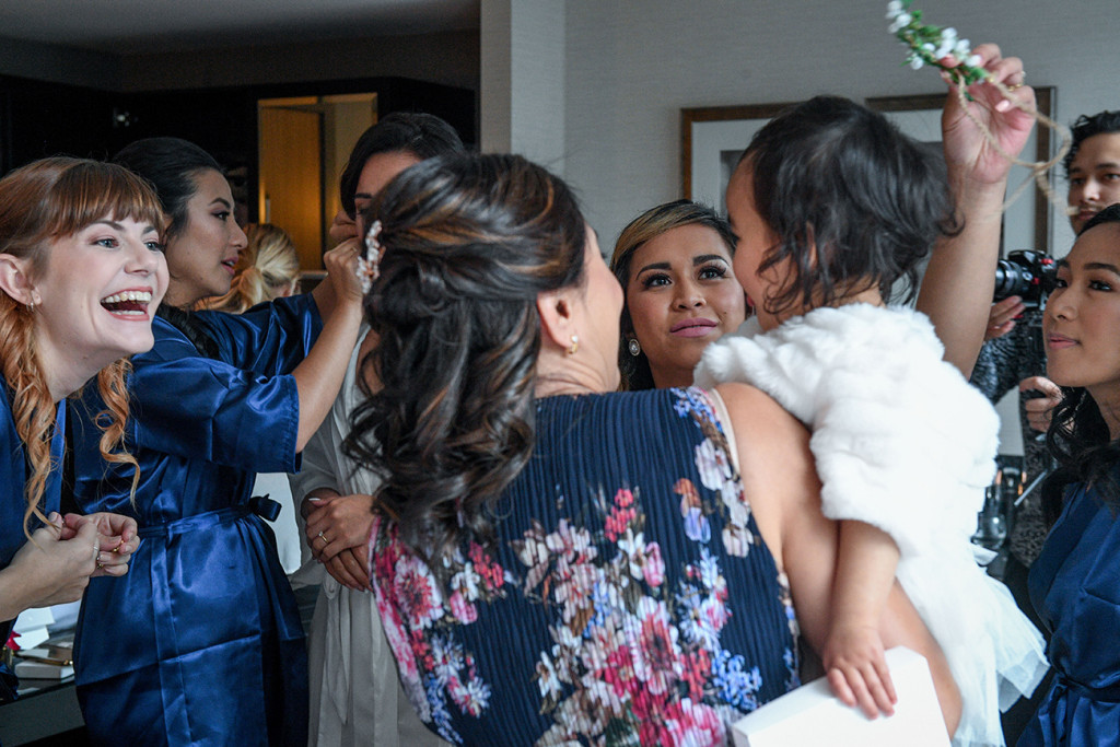 Bridesmaids play around with the bride's daughter during wedding preparation