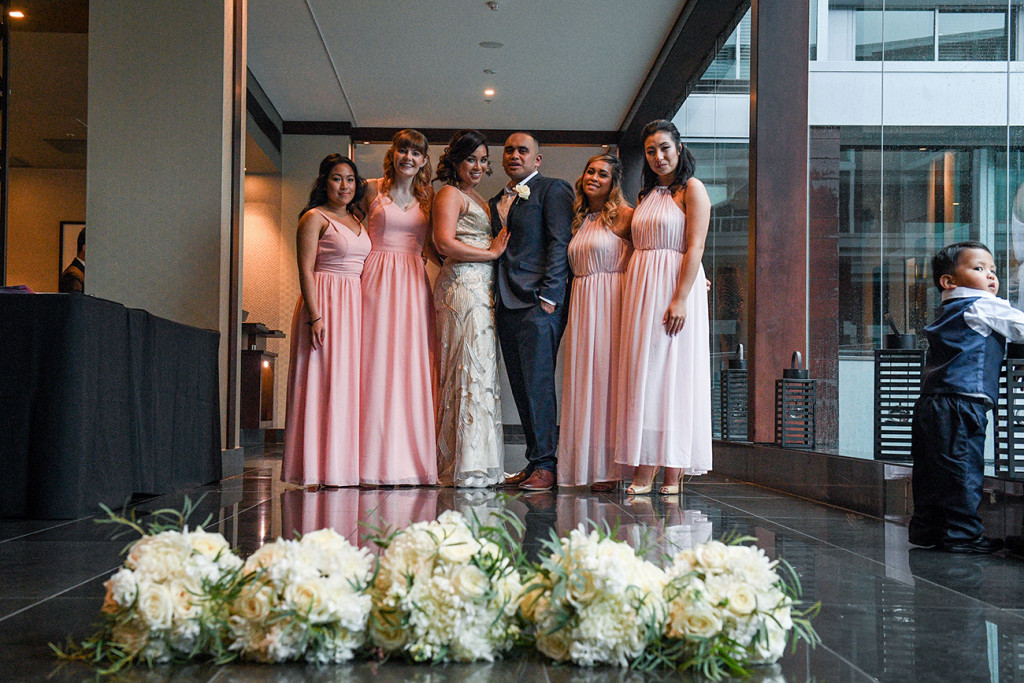 Bride, groom and bridesmaids in pink with white flower bouquet