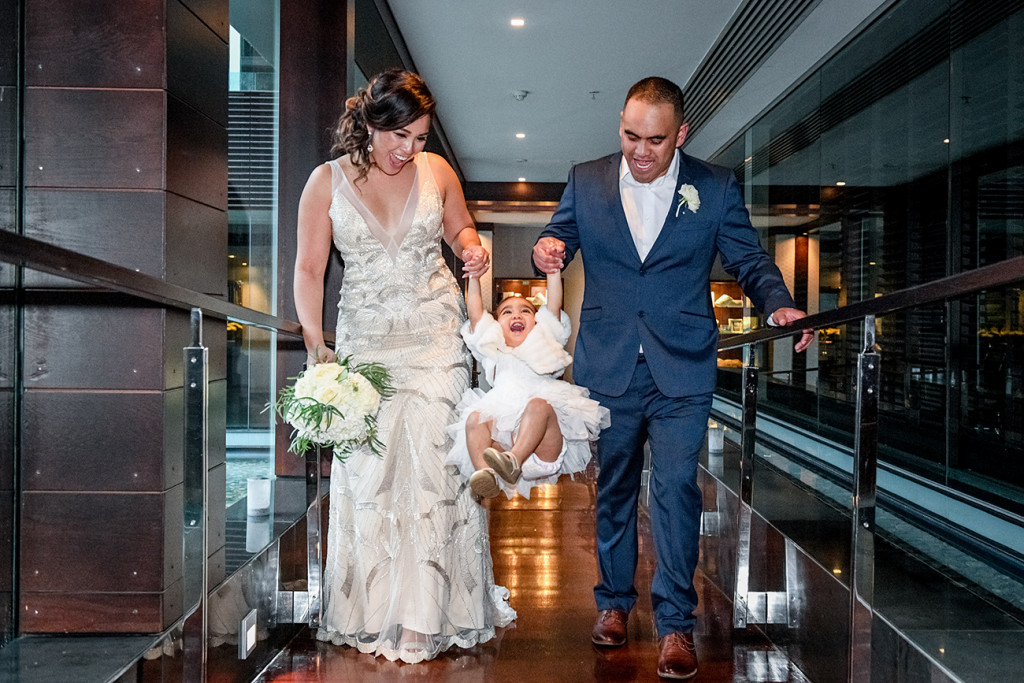 Bride and groom lift their daughter up at the Sofitel Auckland