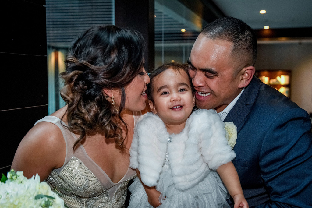 Bride and groom kiss their daughter at their wedding in Sofitel Auckland