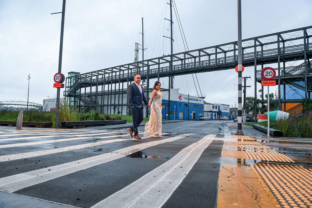 Bride and groom cross the street in wet Auckland streets