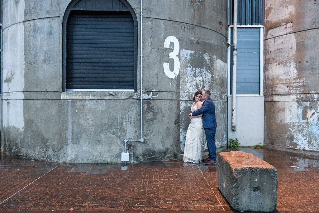 Bride and groom against grey wall in Auckland city wedding photo shoot