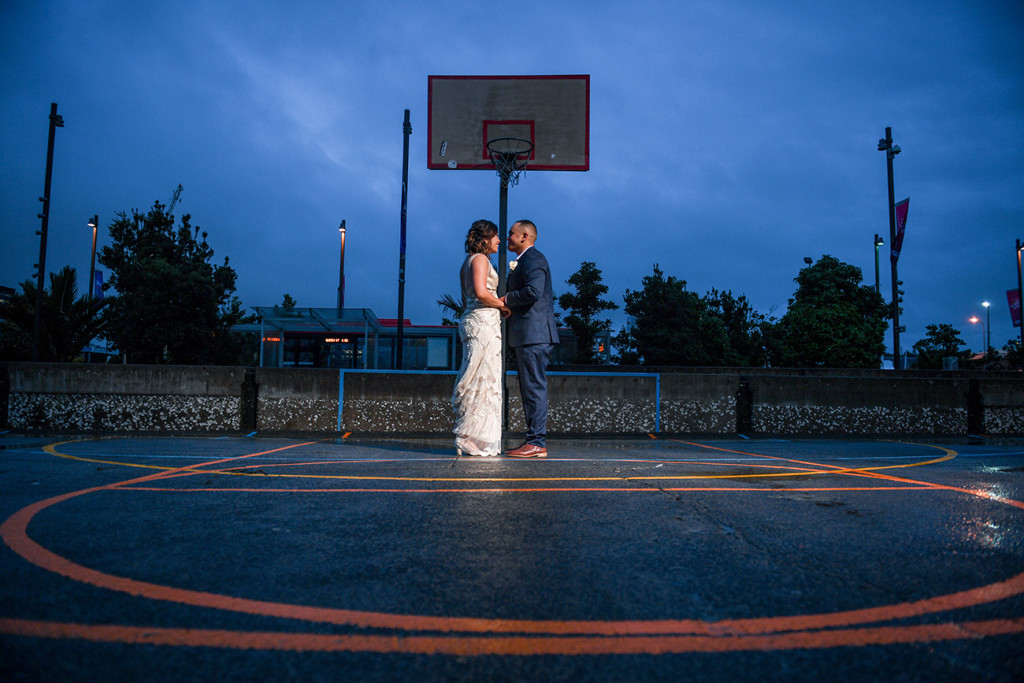 Bride and groom dance on Auckland basketball court at night