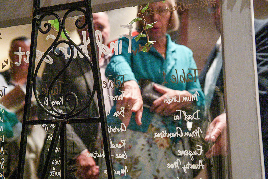 Guests look at the sitting arrangement written on the glass wall