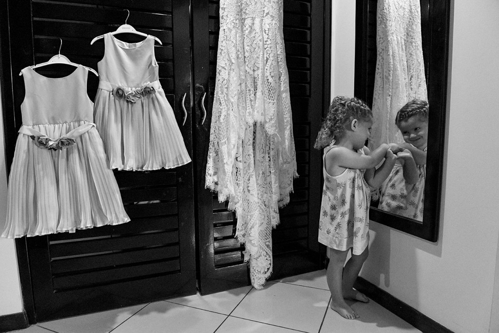 Black and white photo of bride's lace wedding dress and flower girls dress hanging