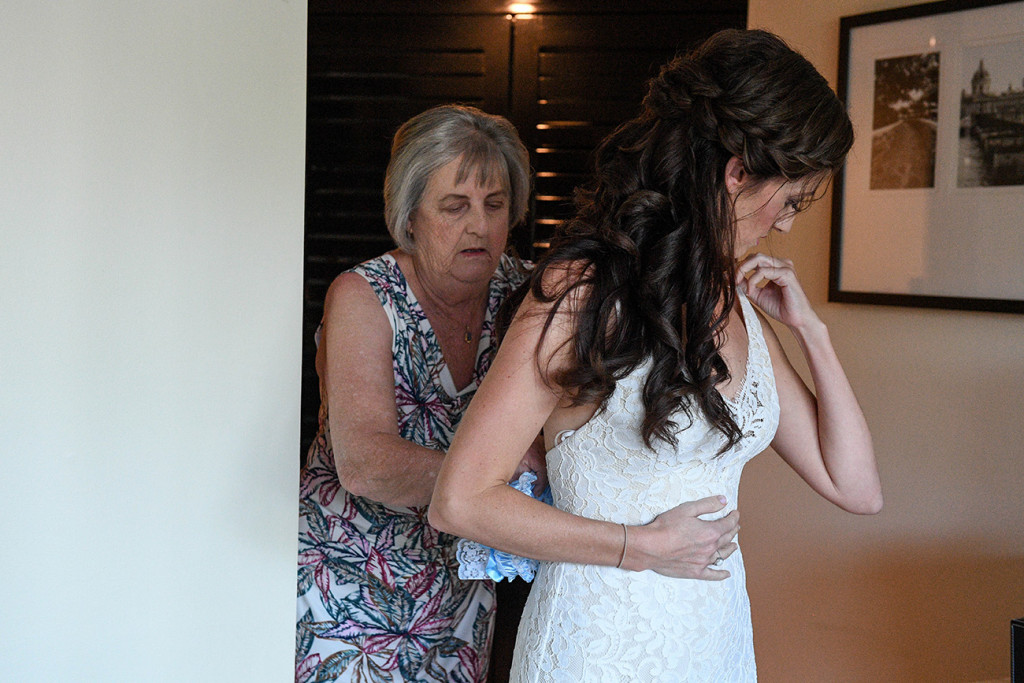 Mom helps bride tie up the back of her wedding dress at Sofitel Fiji wedding