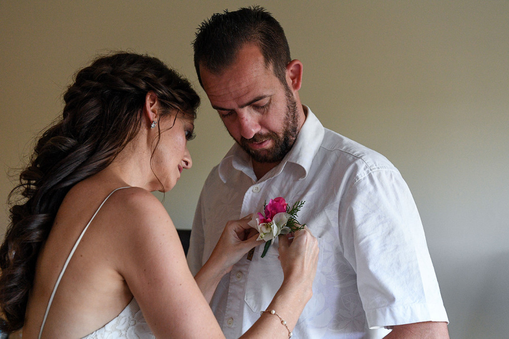 Bride helps groom put on boutonniere