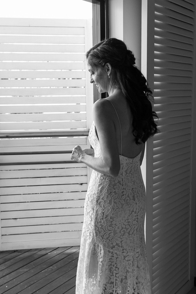 Stunning black and white photo of bride looking out of louvered window