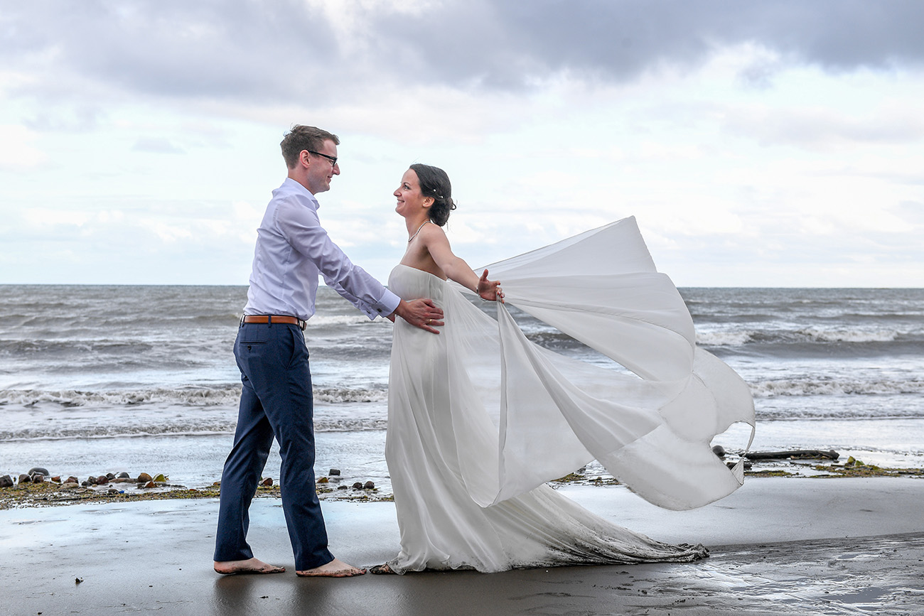 Groom lets his bride 'fly' with her wedding dress train floating in the wind and sea