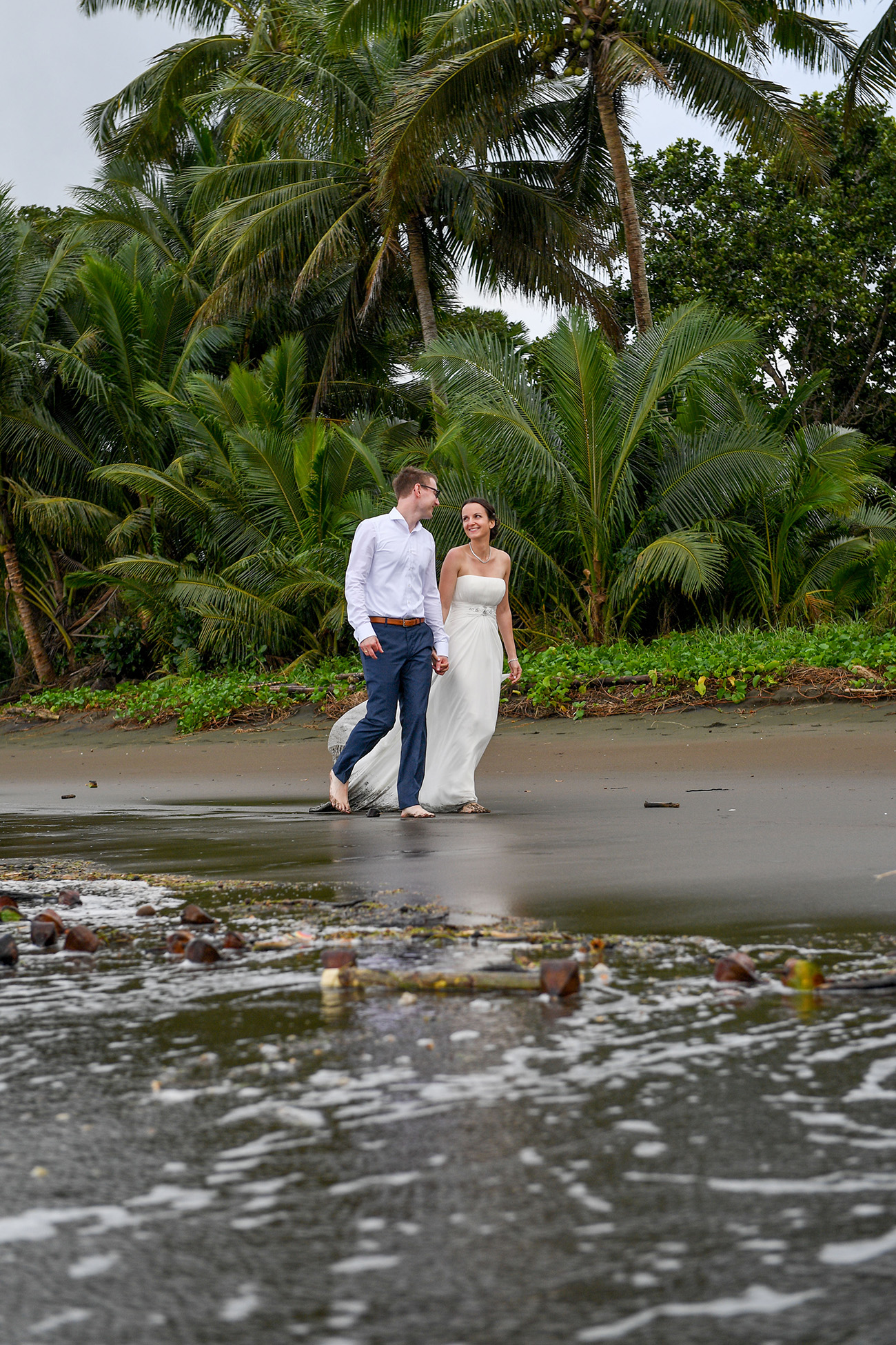 Bride and groom stroll on the shores of Savusavu Island Fiji