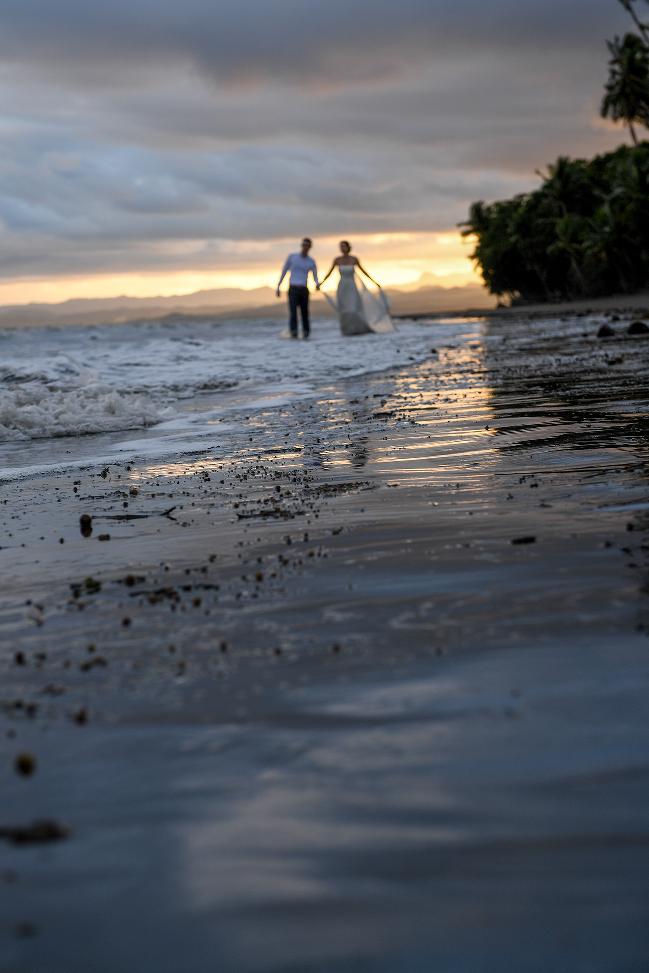 Stunning shot of bride and groom walking on the sea in Fiji sunset