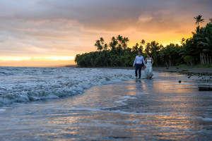 Bride and groom stoll in the sea during fiery Fiji sunset