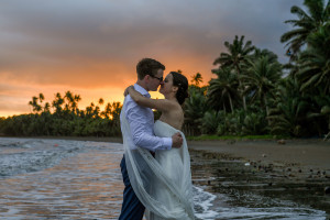 Bride and groom kiss against the sunset