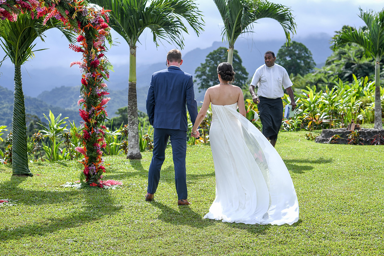 Bride and groom hold hands at the altar of their countryside Fiji wedding