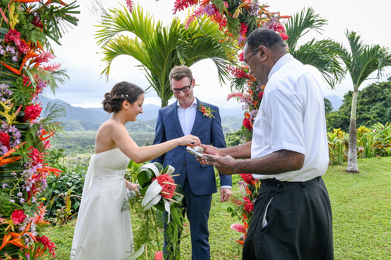 Bride picks ring to put on her groom at the altar in colourful Fiji wedding