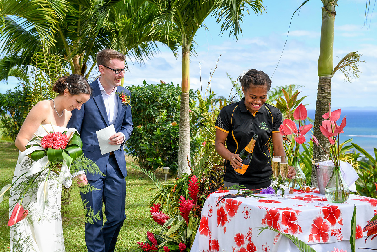 A Fiji guest pours champagne at the altar as the bride and groom watch