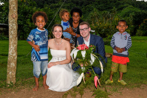 Newly wed couple posing with native Fiji kids at their wedding reception