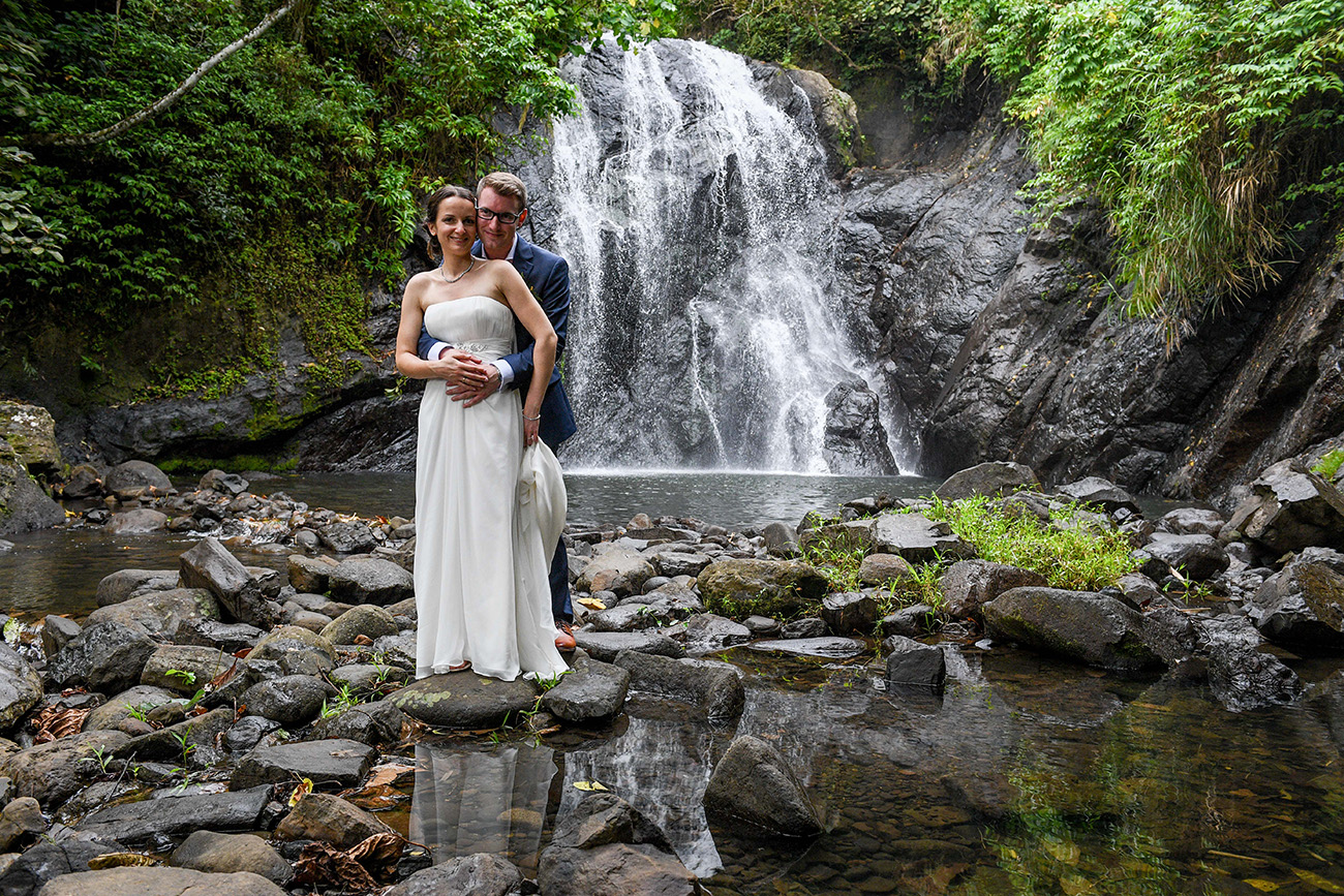 Happily married couple stand in front of stunning waterfall Savusavu Fiji