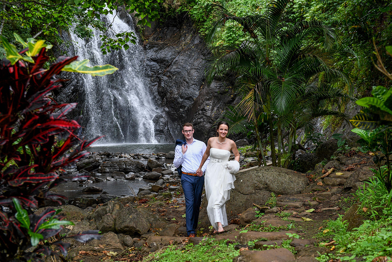 Happily eloped couple walk against a waterfall in Savusavu Island Fiji