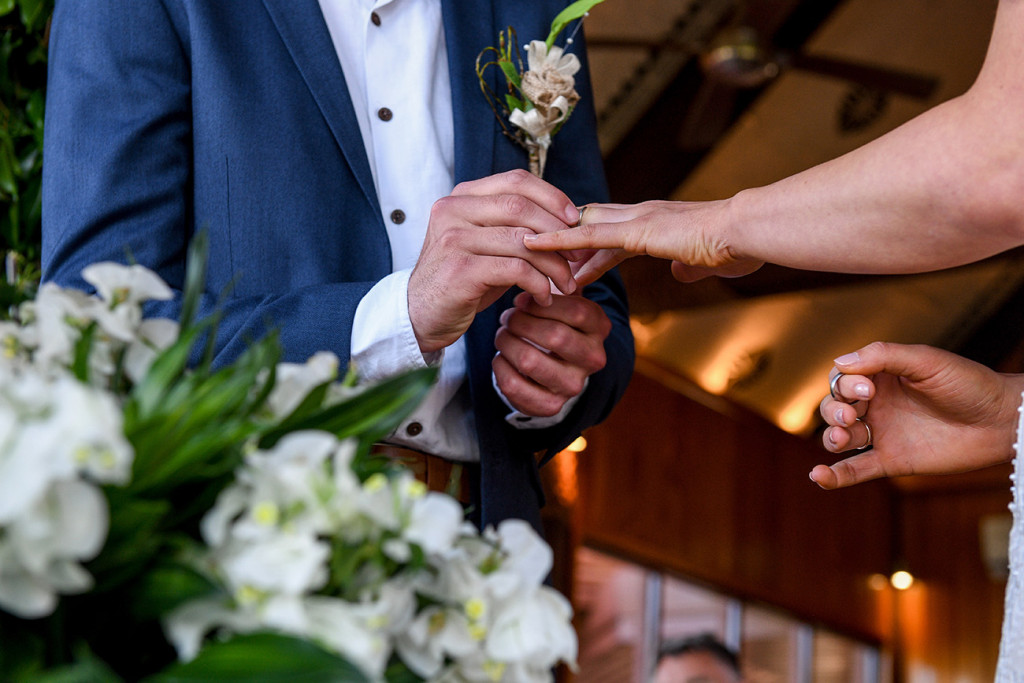 Closeup of groom slipping ring on his boho bride