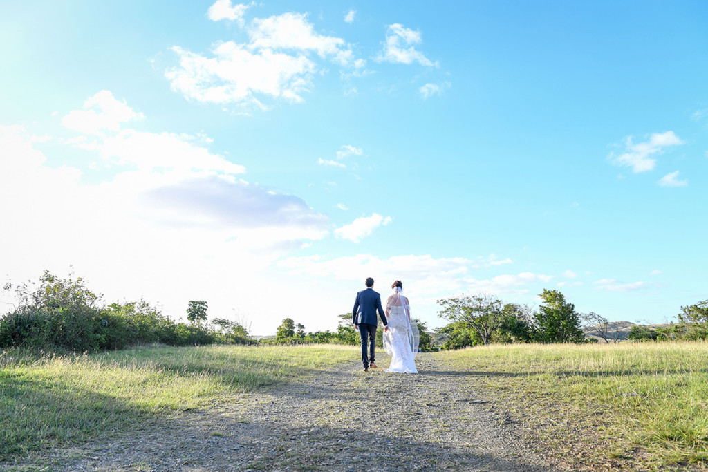 Wideshot of Bride and groom walking into Fiji Greenery