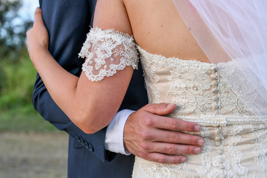 Closeup of grooms hand on bride's hips